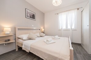 A neatly arranged bedroom with a bed, bedside lamps, a framed picture on the wall, and a window with curtains. - Villa St.vid 3 (Privlaka)