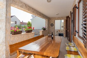 A wooden table with benches, a dartboard, and potted flowers in a stone-walled outdoor area. - Villa St.vid 3 (Privlaka)
