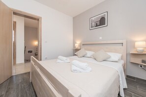 A bedroom with a wooden bed, white bedding, and a framed picture on the wall. - Villa St.vid 3 (Privlaka)