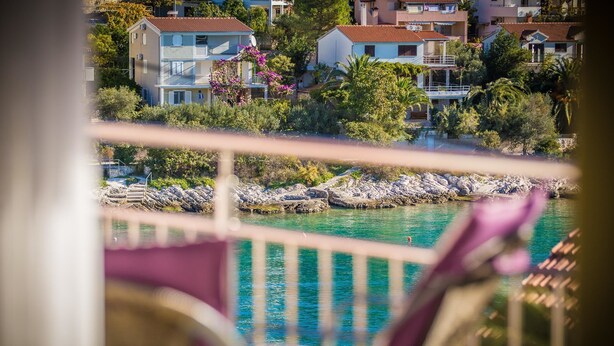 A view from a balcony overlooking a coastal area with buildings and a rocky shoreline. - Apartments The Palms (Okrug)