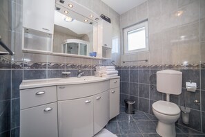 A modern bathroom with a vanity, sink, mirror, and toilet.