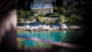 A coastal property with a stone facade, a balcony, and a view of the sea. - Apartments The Palms (Okrug)