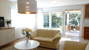 A modern living room with a beige sofa, a white coffee table, and a hanging light fixture. - Holiday House Lidija (Medulin)