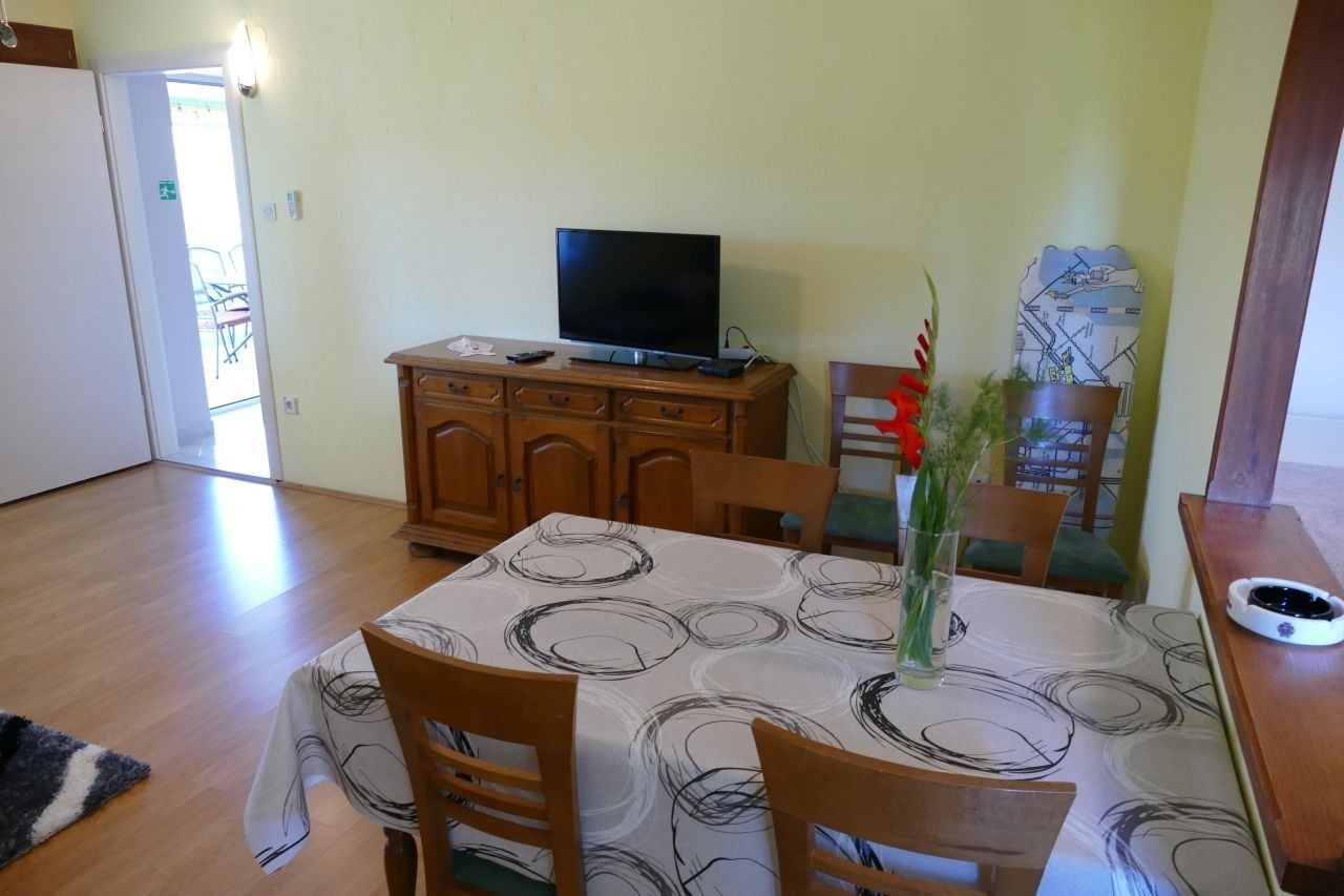 A dining area with a table set for two, a television on a wooden cabinet, and a map on the wall.