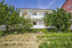 A two-story building with a white facade, balconies, and a garden in front. - Apartment Ante Kampor (Rab)