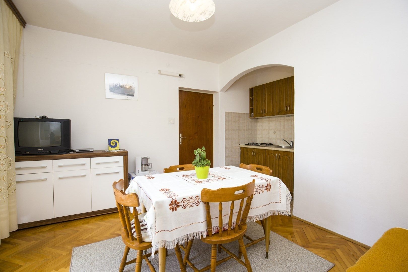 Un espacio habitable compacto con comedor, kitchenette y televisor.