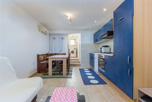 Una cocina compacta con armarios azules, una zona de comedor con mesa y sillas, y una pequeña kitchenette.