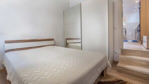 A bedroom with a bed, a wardrobe, and a staircase leading to a bathroom. - Apartment Arena (Pula)