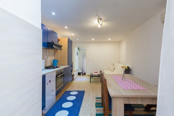 A compact kitchen with modern appliances, a dining area with a table and chairs, and a small seating area with a sofa. - Apartment Arena (Pula)