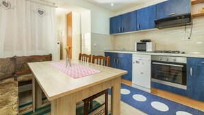 A compact kitchen with blue cabinets, a microwave, a stove, and a dishwasher. - Apartment Arena (Pula)