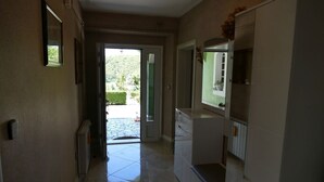 Un pasillo con una puerta que da a un jardín, un radiador y una encimera con un espejo.