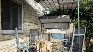 An outdoor patio with a table and chairs, a covered seating area, and a window. - Apartment Lili Pula (Pula)