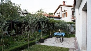 Ein Innenhof mit einer Steinterrasse, einem Tisch mit Stühlen und Blumentöpfen.