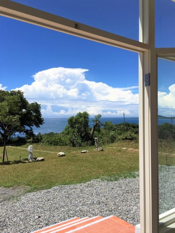 A view from inside a building looking out to a grassy area with trees and a body of water.