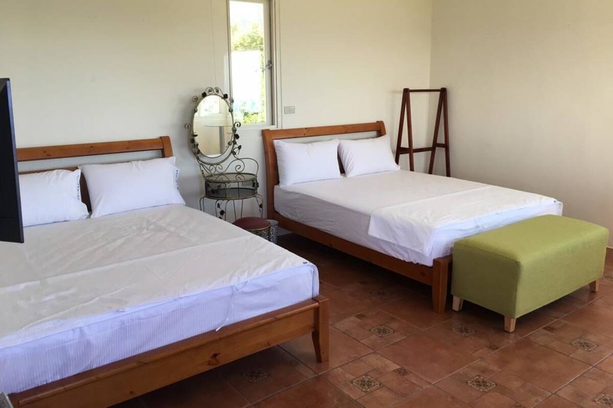 A room with two wooden beds, a green bench, a mirror, and a ladder.