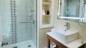 A modern bathroom with a glass-enclosed shower, a white sink, and a large mirror.
