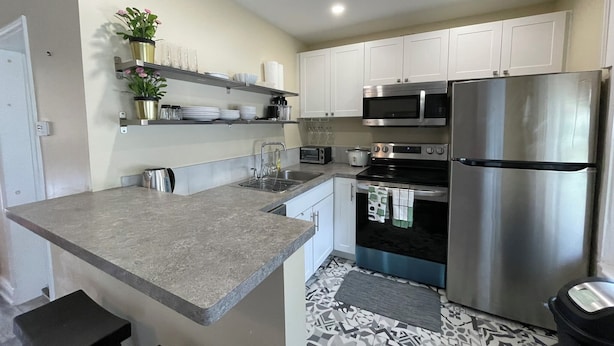 A modern kitchen with white cabinets, stainless steel appliances, and a grey countertop.