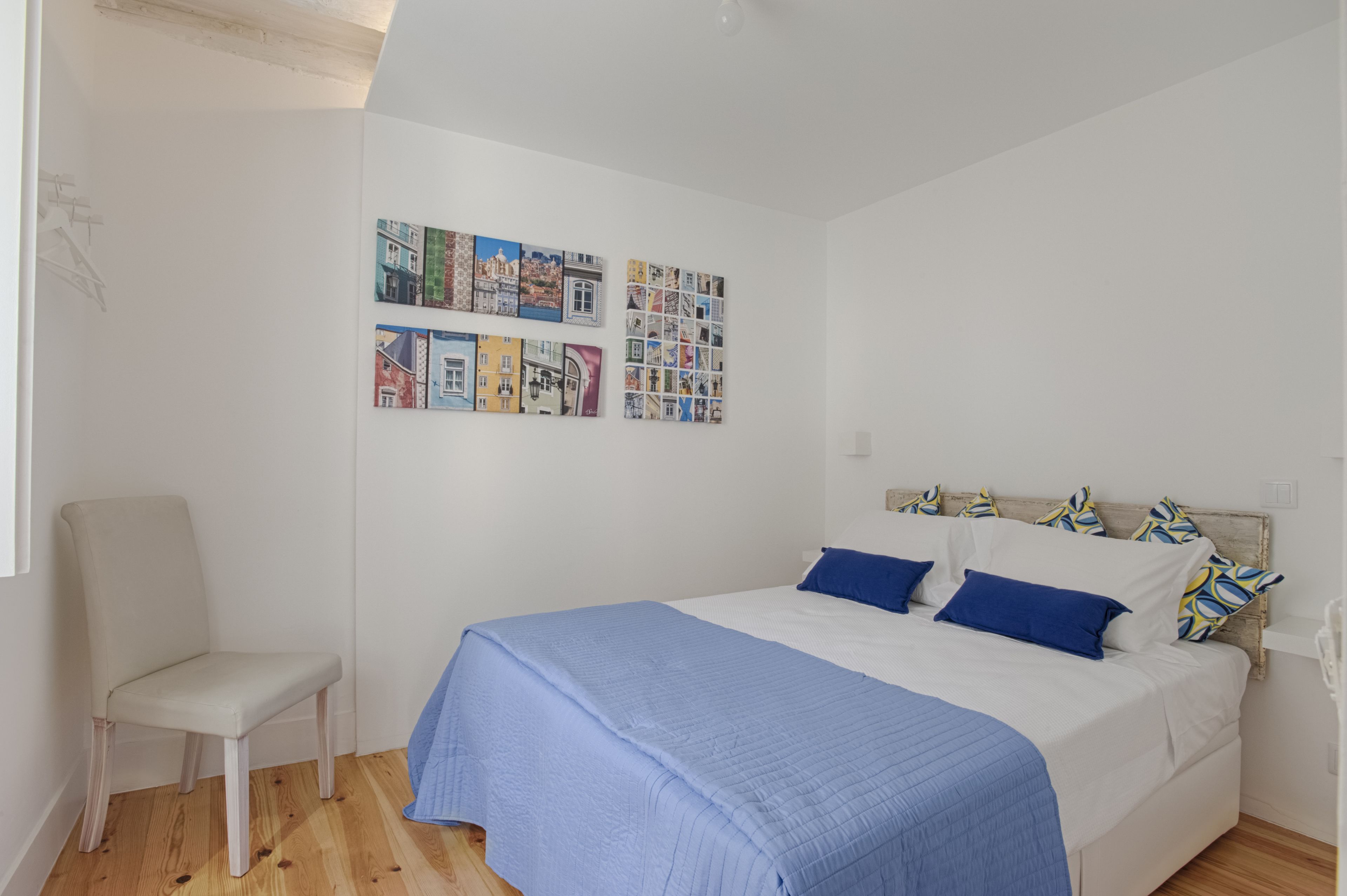 A bedroom with a bed, a chair, and a wall with postcards.