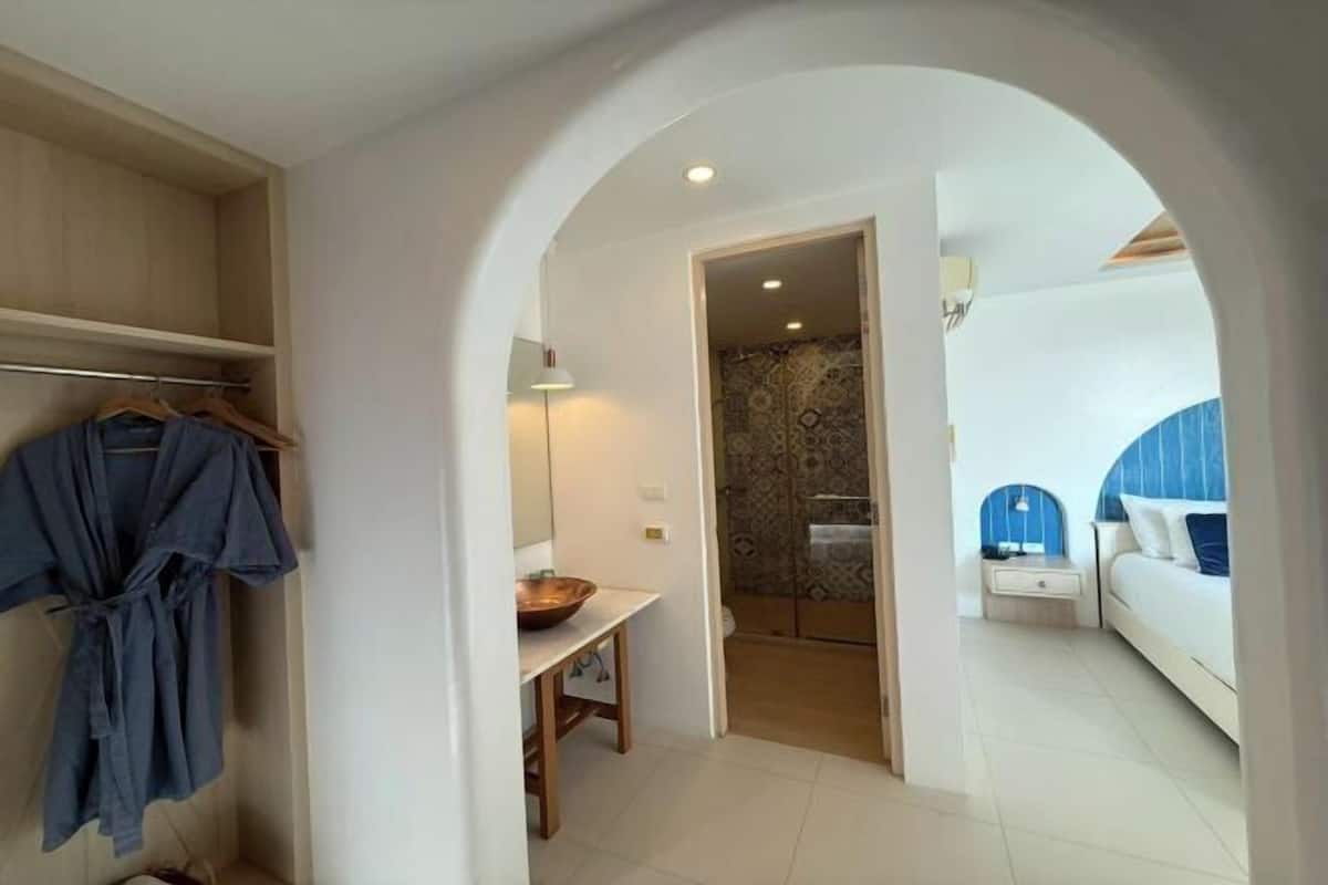 Un couloir menant à une chambre à coucher équipée d’un lit, d’une table de chevet et d’une armoire suspendue.