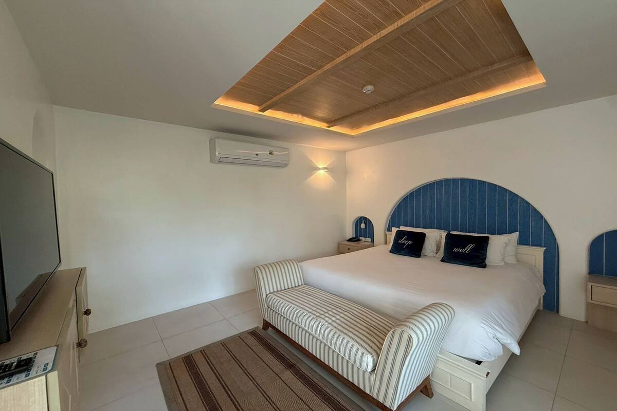 Une chambre à coucher comprenant un lit, une télévision, une table de chevet et une lampe fixée au plafond.