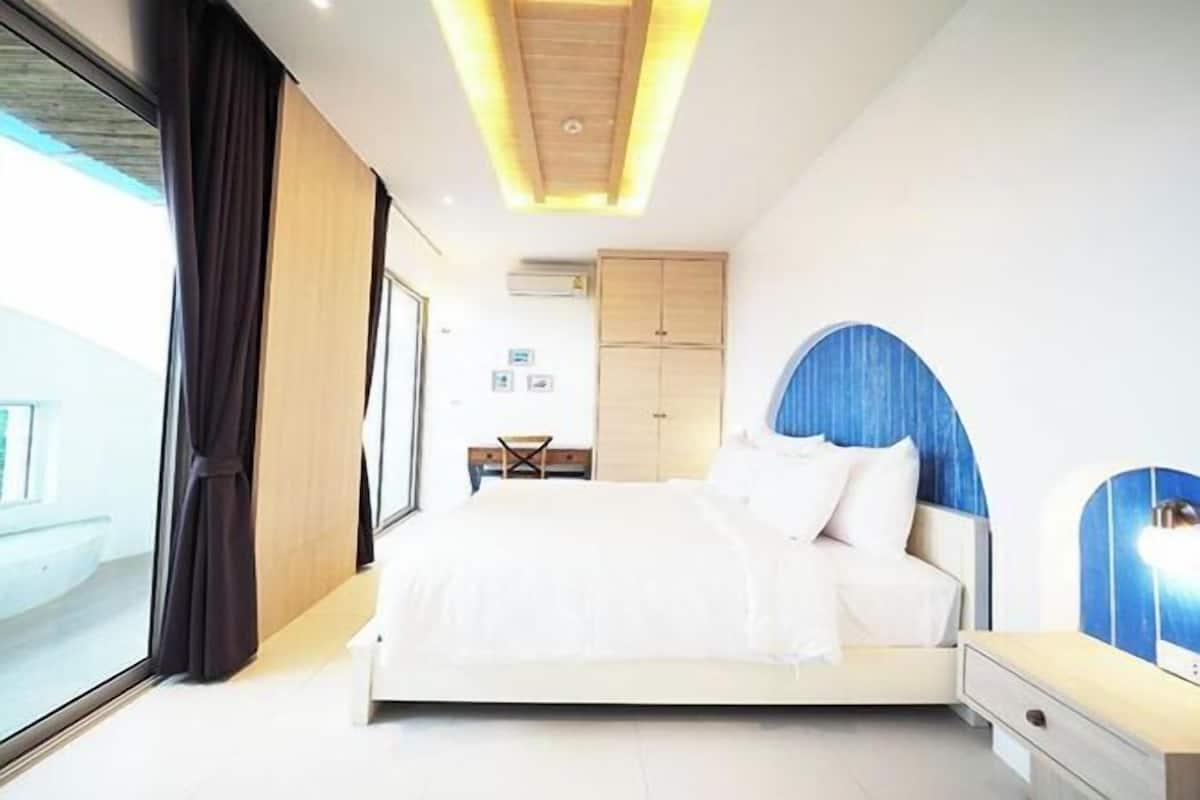 Une chambre moderne avec un grand lit, un bureau et une vue par la fenêtre.