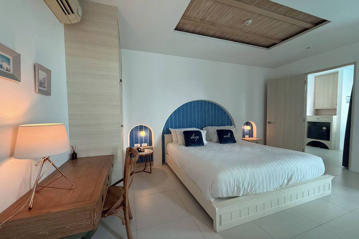 Une chambre à coucher avec un lit, des lampes de chevet, un bureau et une chaise.