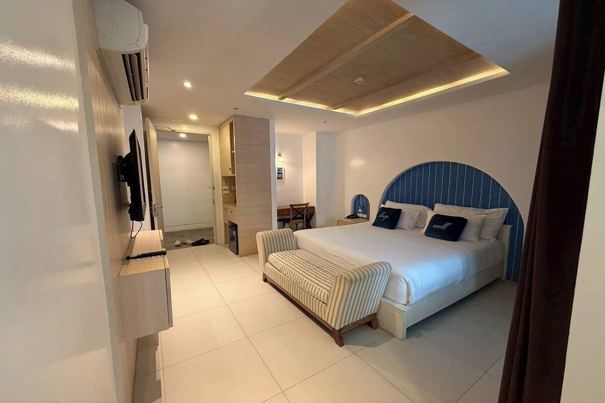 Une chambre d’hôtel moderne, dotée d’un grand lit, d’un bureau et d’une télévision.
