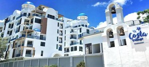 A multi-story hotel with balconies, a bell tower, and a sign reading 'Costa Village Bangsaray.' - Costa Village Jacuzzi Bangsaray (Sattahip)