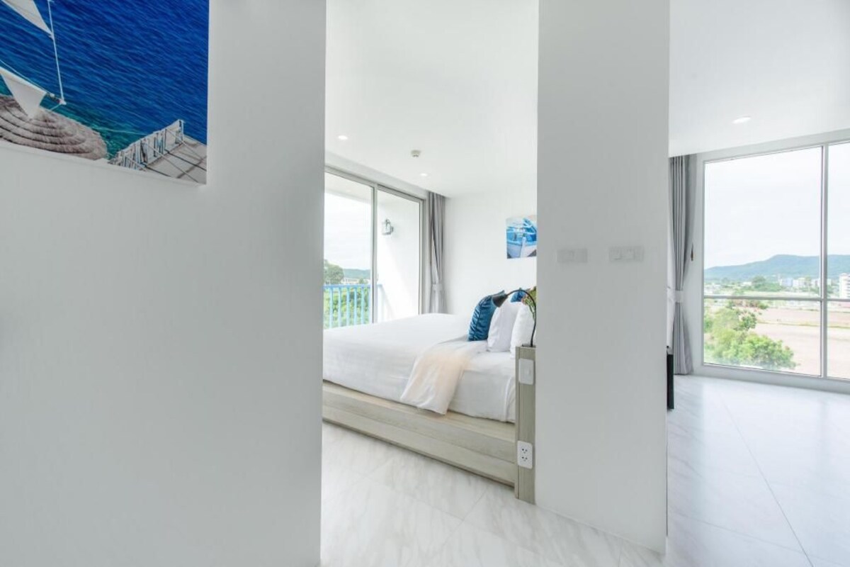 Quarto de hotel moderno com uma cama grande, vista para o mar e varanda.