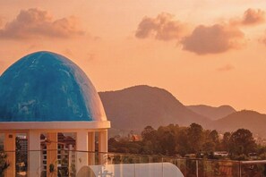 A building with a large blue dome, a fenced area, and a mountainous landscape in the background. - Costa Village Jacuzzi Bangsaray (Sattahip)
