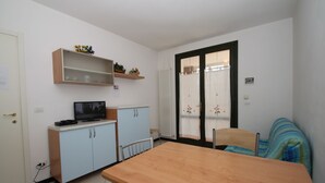 Eine kleine Küche mit Holztisch, hellblauen Schränken und einem Fernseher.
