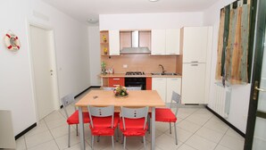 Eine kompakte Küche mit weißen Schränken, einem Holzespeisetisch mit vier Stühlen und einer kleinen Arbeitsfläche mit Spüle.