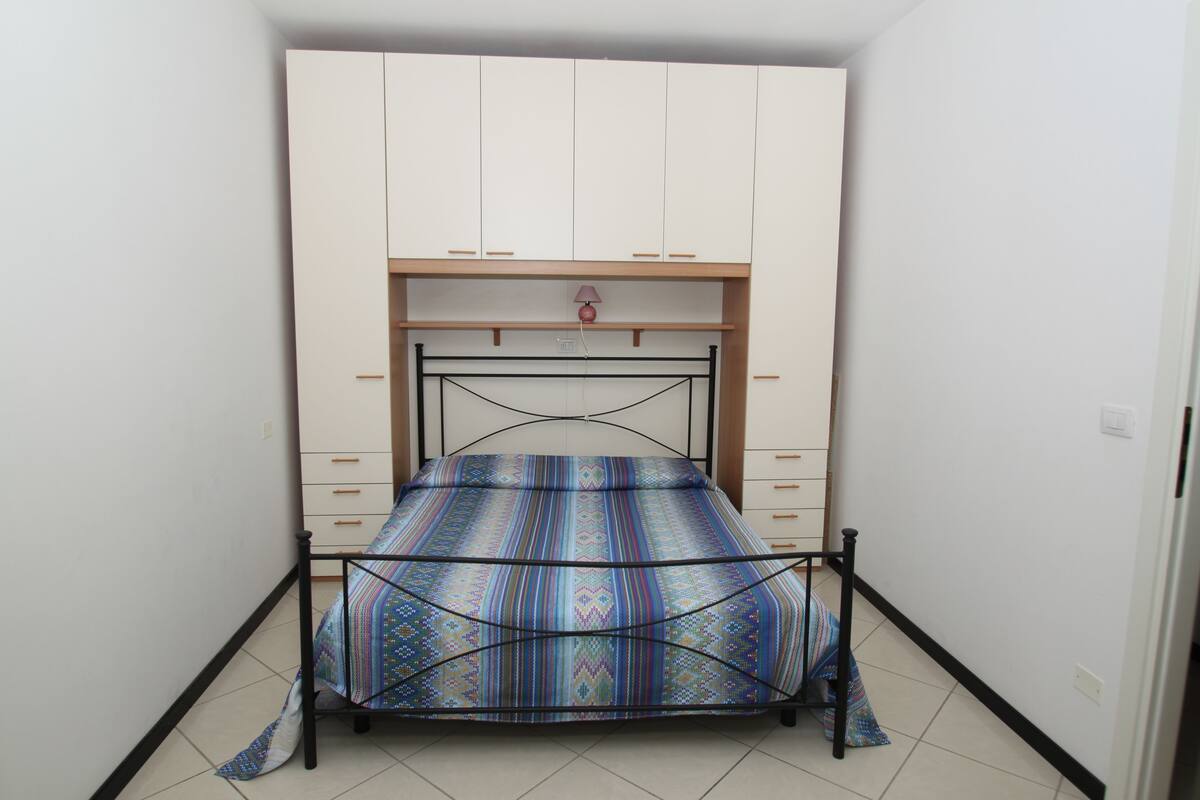 Un dormitorio con cama, armario y escritorio.