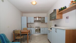 Eine kleine Küche mit hellblauen Schränken, einem Holztisch mit Stühlen und einem Fliesenboden.