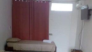 A room with two beds, a TV mounted on the wall, and a window with curtains. - Posada Rocky 2 (San Andrés)