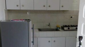A compact kitchen with white cabinets, a refrigerator, a sink, and a stove. - Posada Rocky 2 (San Andrés)