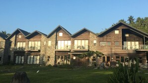 A row of modern, multi-story houses with stone and wood exteriors, balconies, and a well-maintained lawn. - Coconut Beach Homestay (Beinan)
