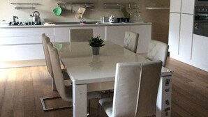 A modern kitchen with white cabinets, a dining table with chairs, and a built-in oven. - home in the historic center of Catania (Catania)