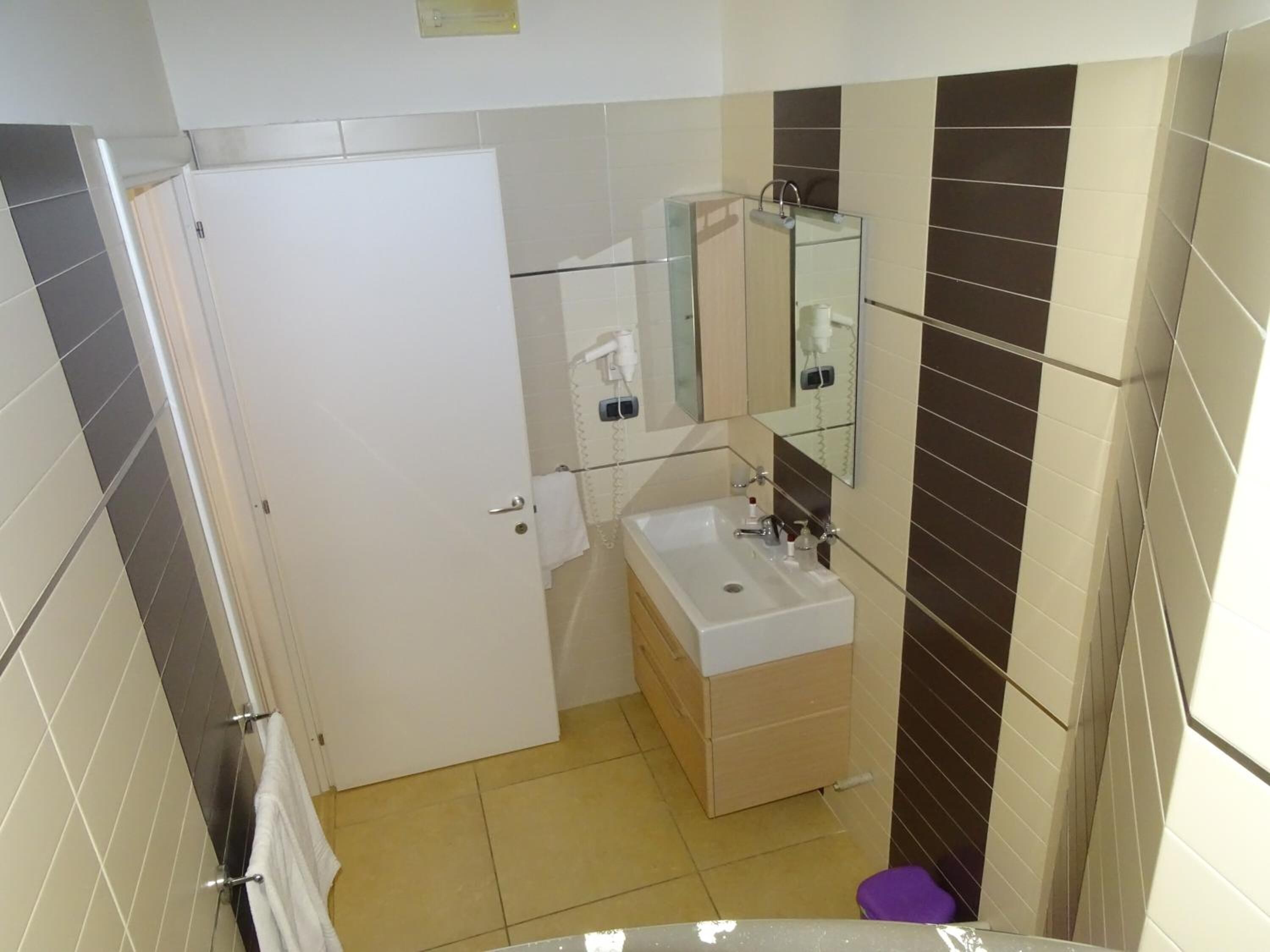 Une salle de bain avec une porte blanche, un lavabo avec un miroir et un porte-serviettes.