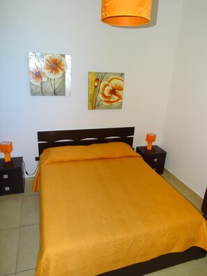 Un dormitorio con una cama, dos mesitas de noche, dos lámparas y dos cuadros en la pared.