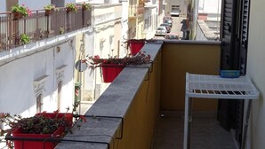 A narrow balcony with red flower pots, a white metal shelf, and a yellow wall. - B&B Soleluna (Veglie)