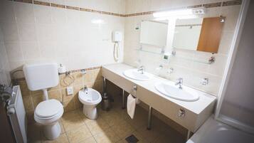 Un baño con dos lavamanos, un inodoro, un bidé y un espejo.