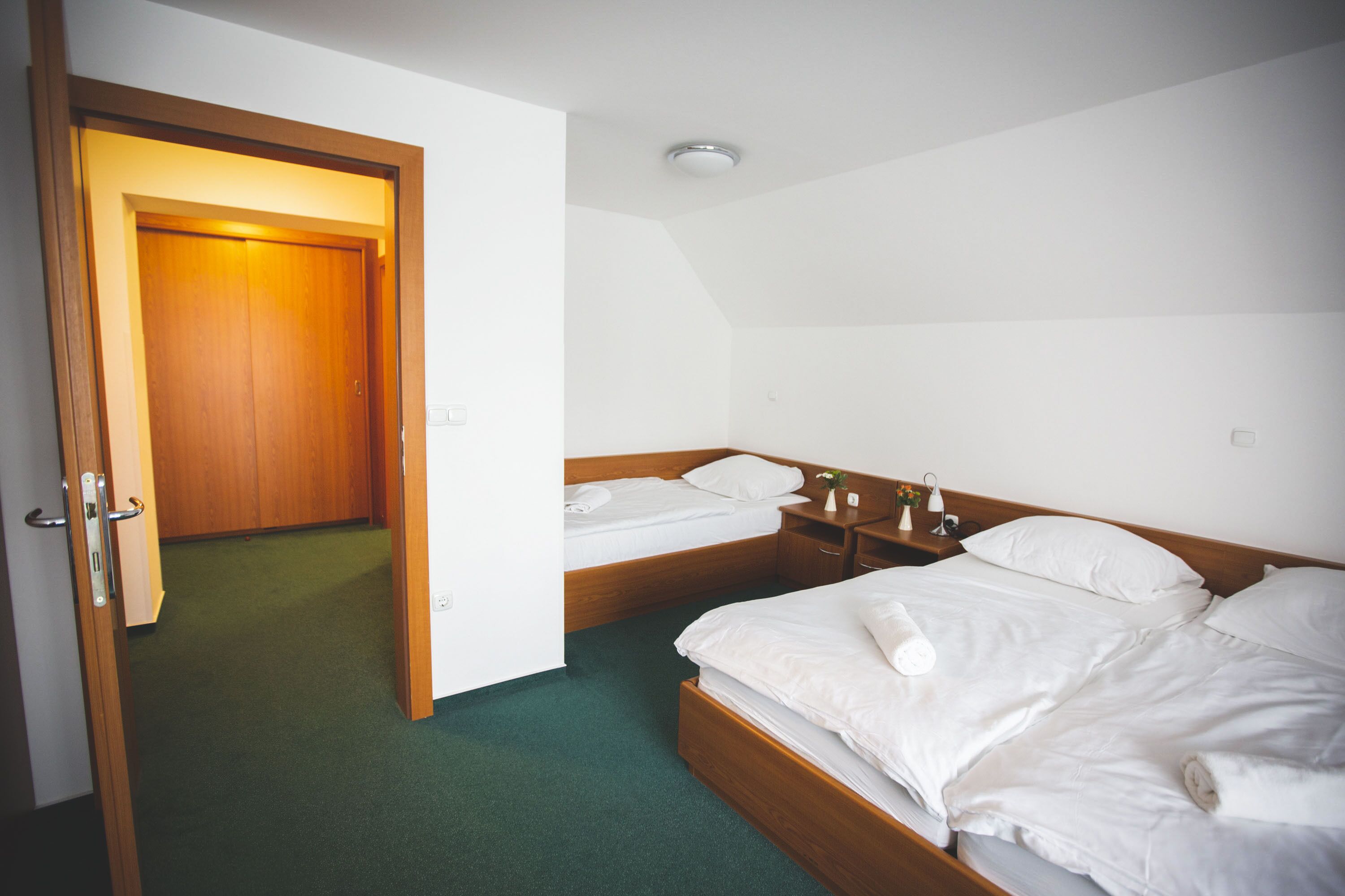 Une chambre d’hôtel avec un lit en bois, un lit plus petit et une table de chevet avec une lampe.