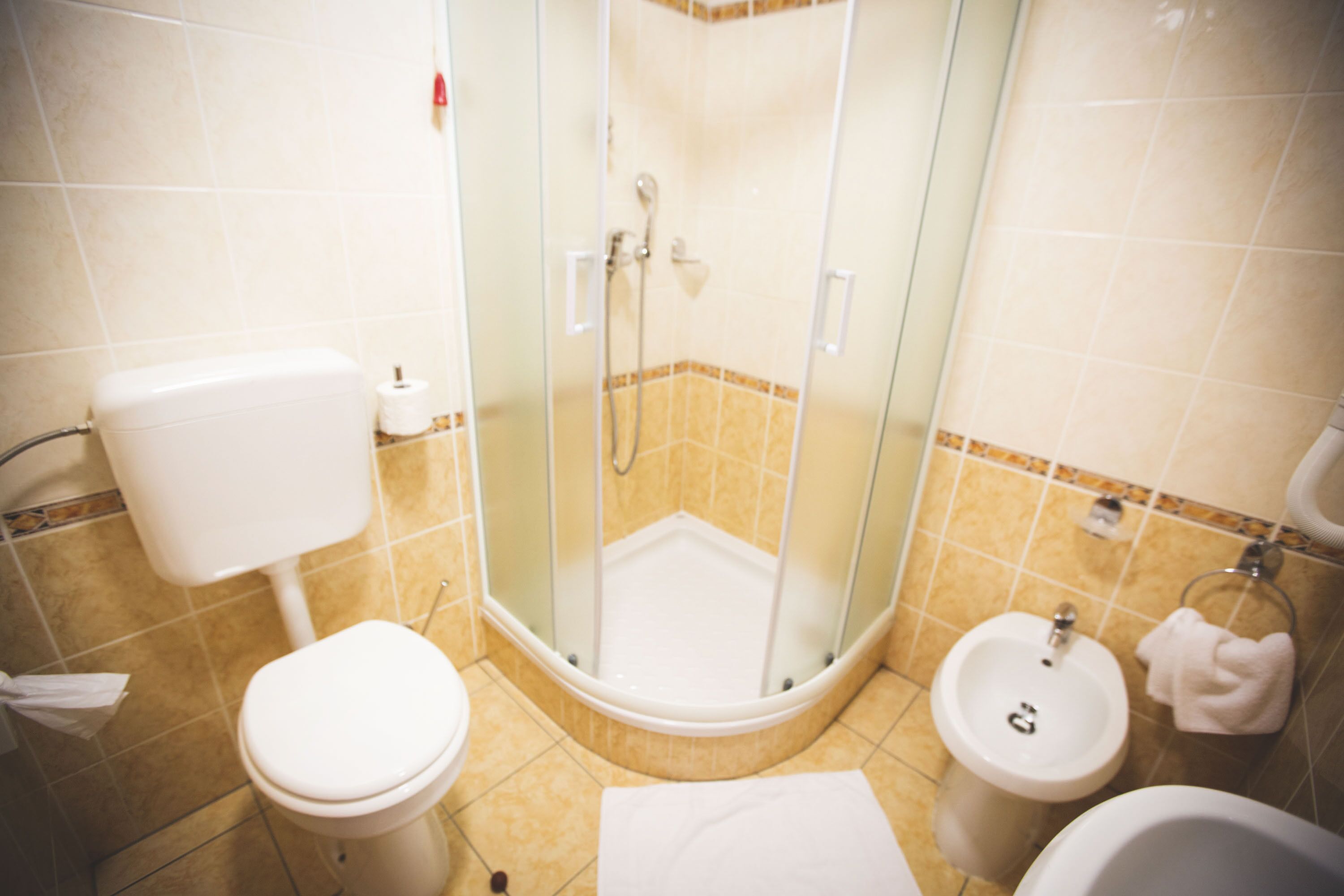 Un bany amb vàter, bidet i plat de dutxa amb envàs de vidre.