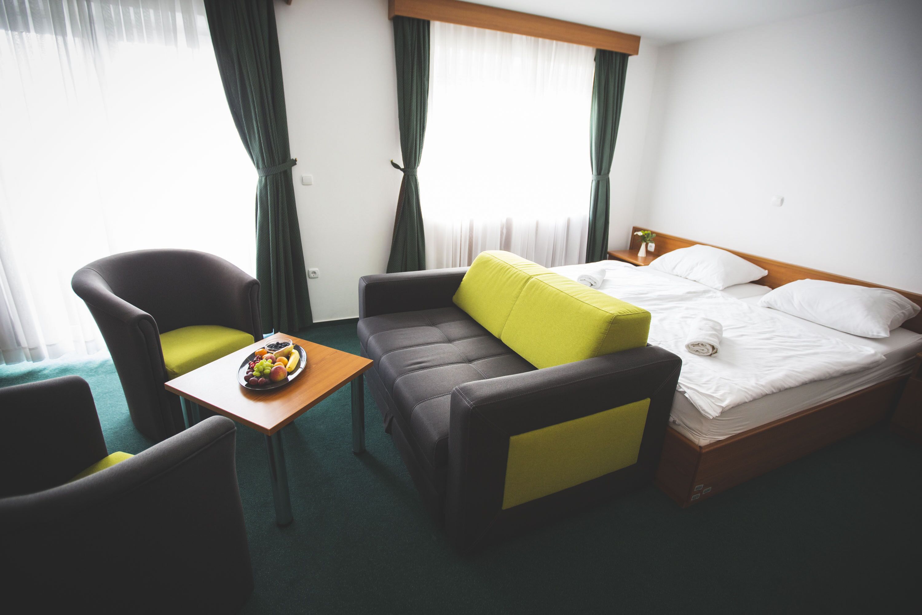 Een hotelkamer met een bed, een bank, een klein tafeltje met fruit en een stoel.