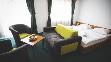 Een hotelkamer met een bed, een bank, een klein tafeltje met fruit en een stoel.