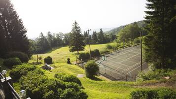 A tennis court surrounded by lush greenery and trees.