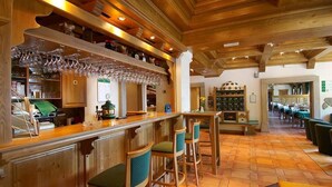 A bar area with wooden bar counters, hanging wine glasses, and bar stools. - Hotel Tisa (Hoce-Slivnica)