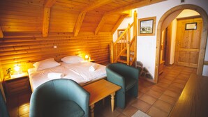 A wooden cabin with a bed, two chairs, a table, and a staircase. - Hotel Tisa (Hoce-Slivnica)