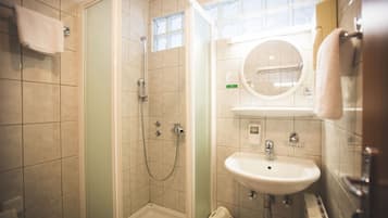 Un baño con ducha, lavabo y espejo.